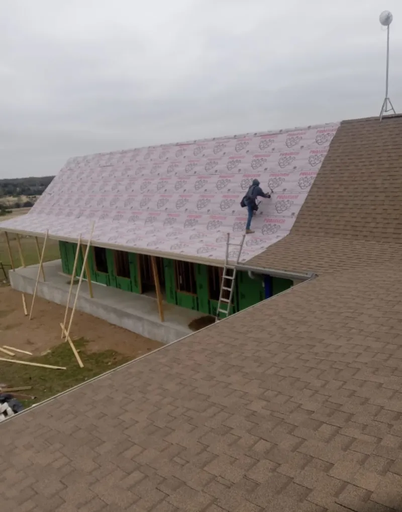 Worker preparing underlayment for a metal roof installation in Highland